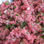 Mixing ground meat, chopped parsley, onions, and tomatoes