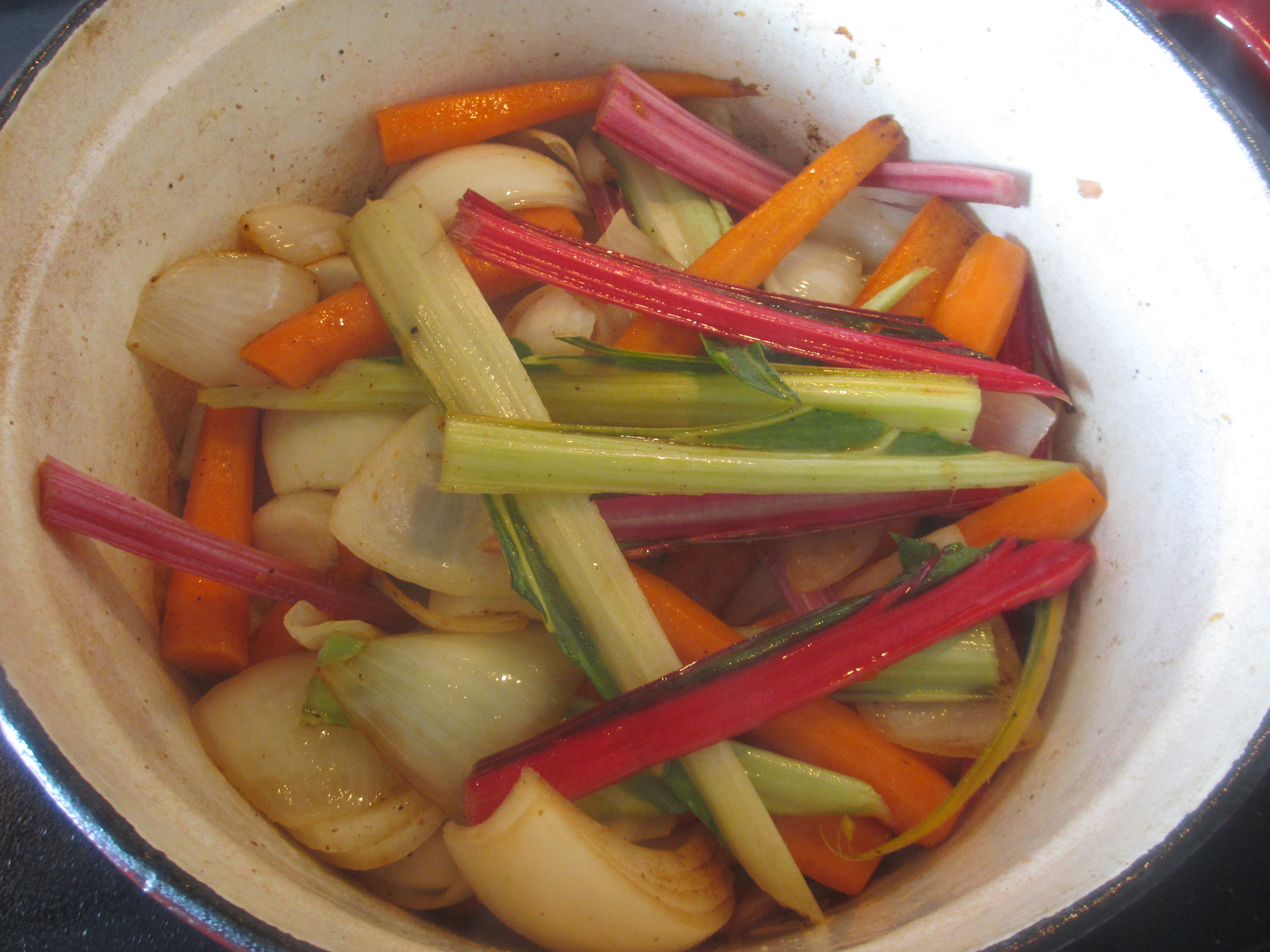 Carrots and onions in a pot with swiss chard stalks