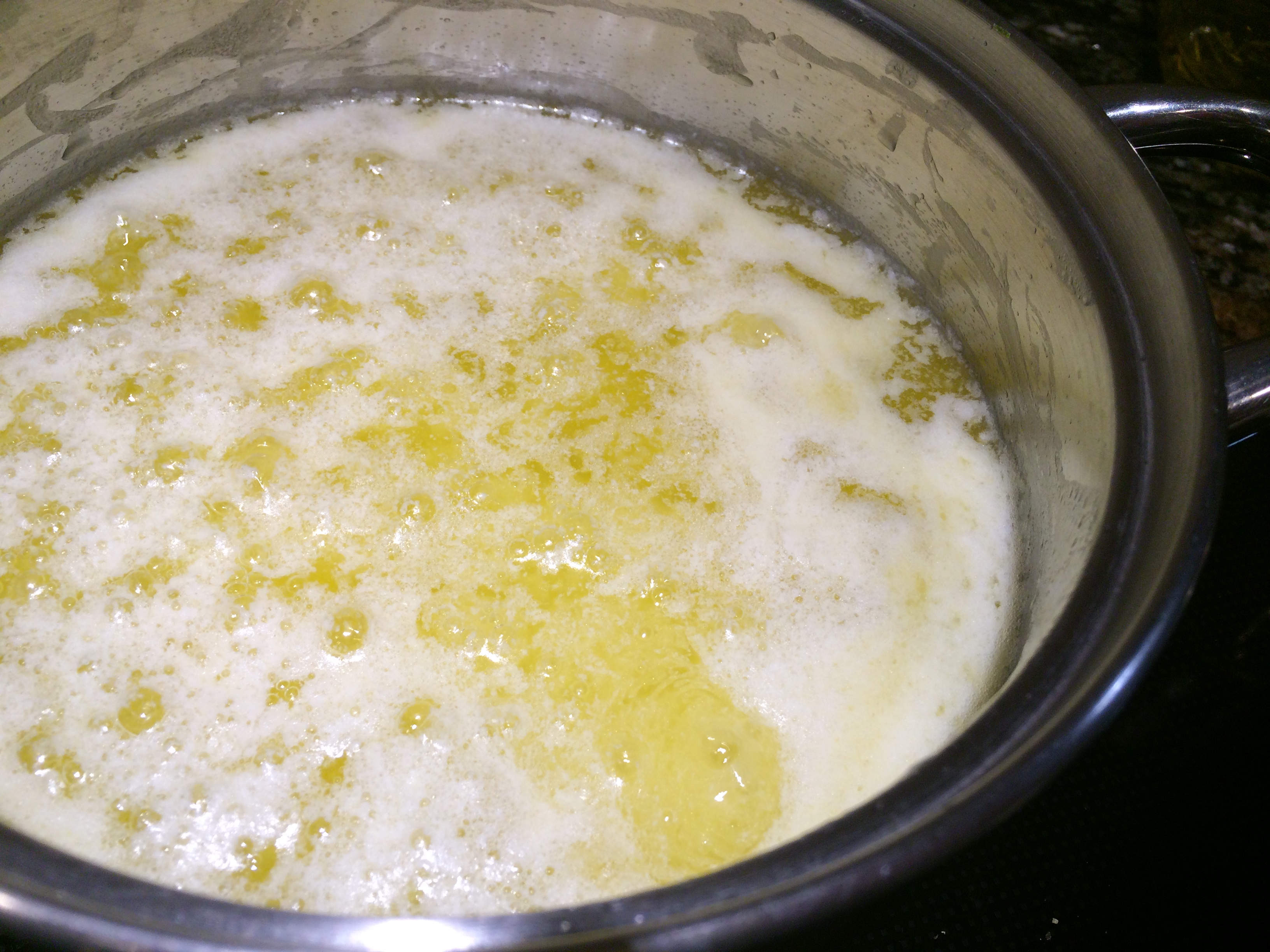 Curds and whey being separated in a pot