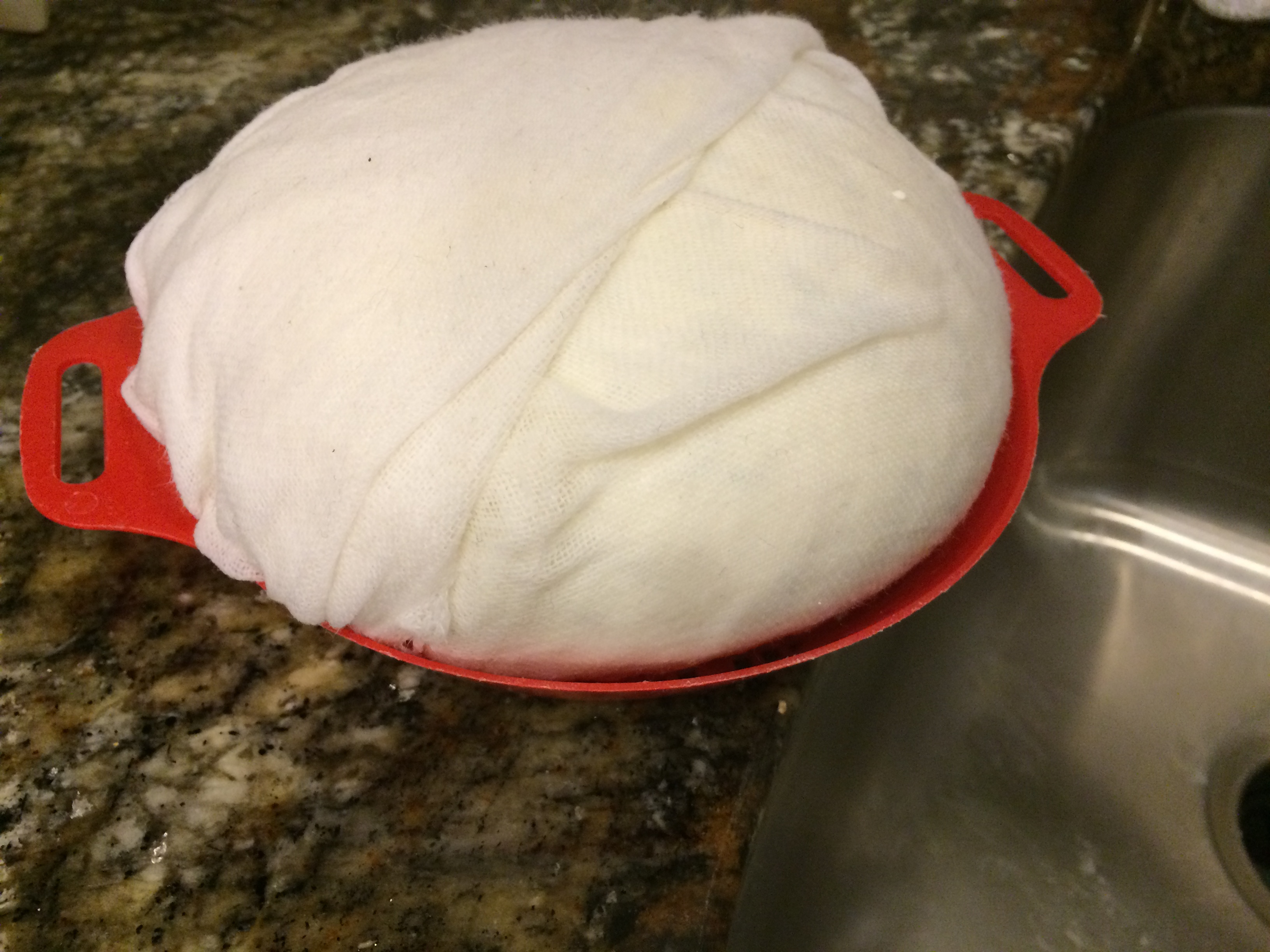 Cheese curds wrapped in a cheese cloth, in a strainer