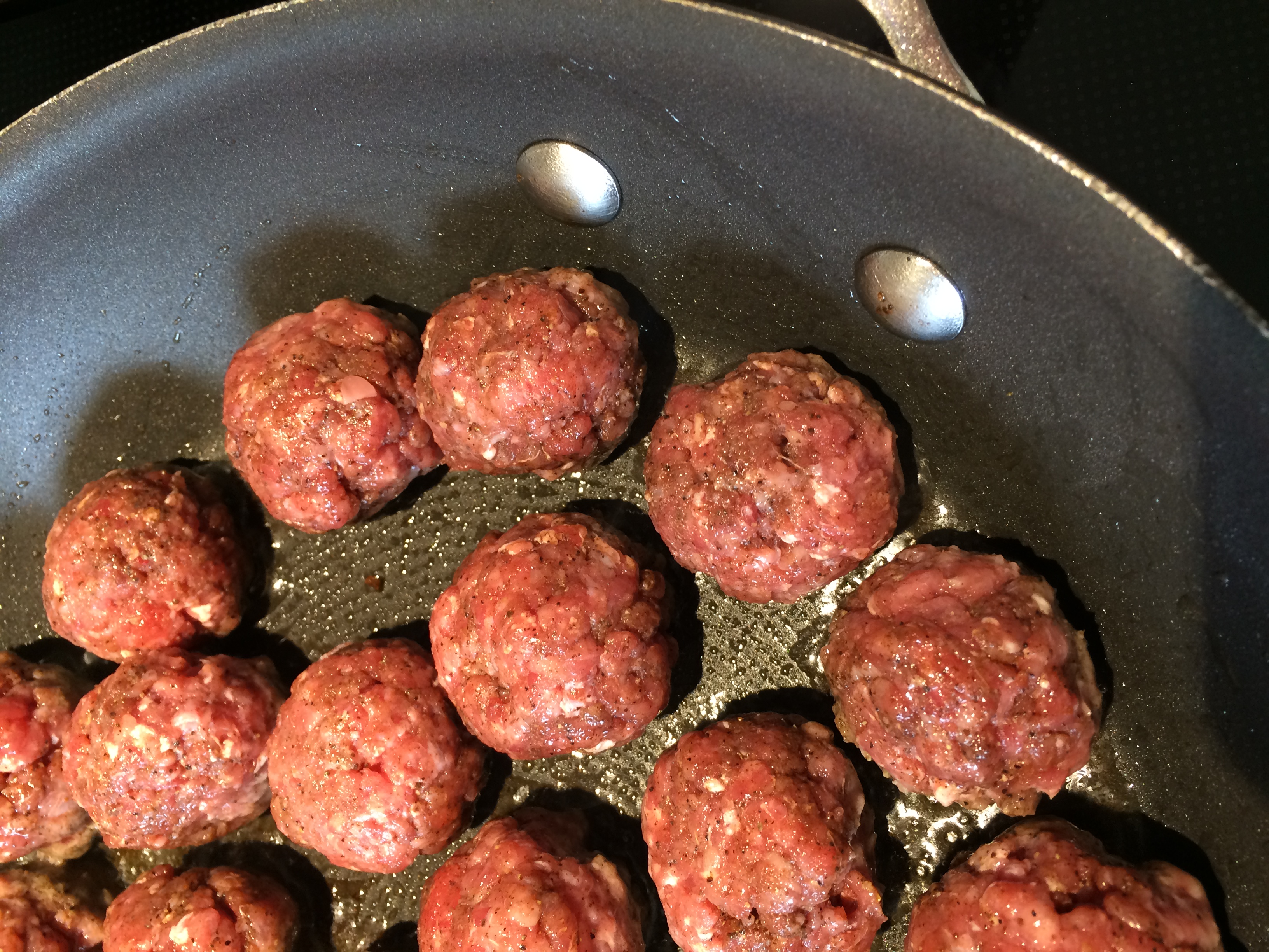 Spiced meatballs cooking in a sauce pan