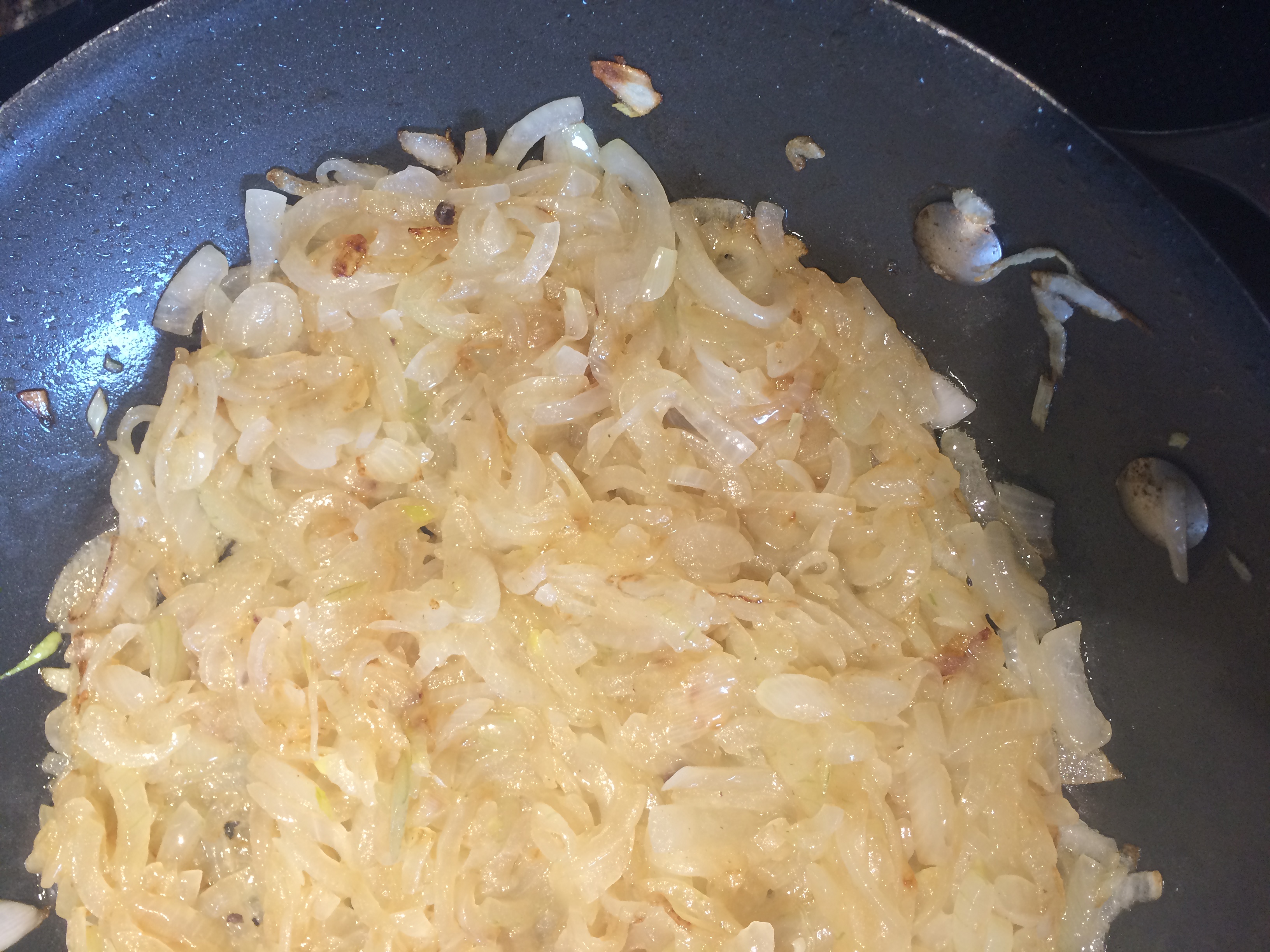 Thinly sliced onions being cooked in a frying pan