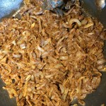 Onions being cooked in a frying pan with spices and lemon