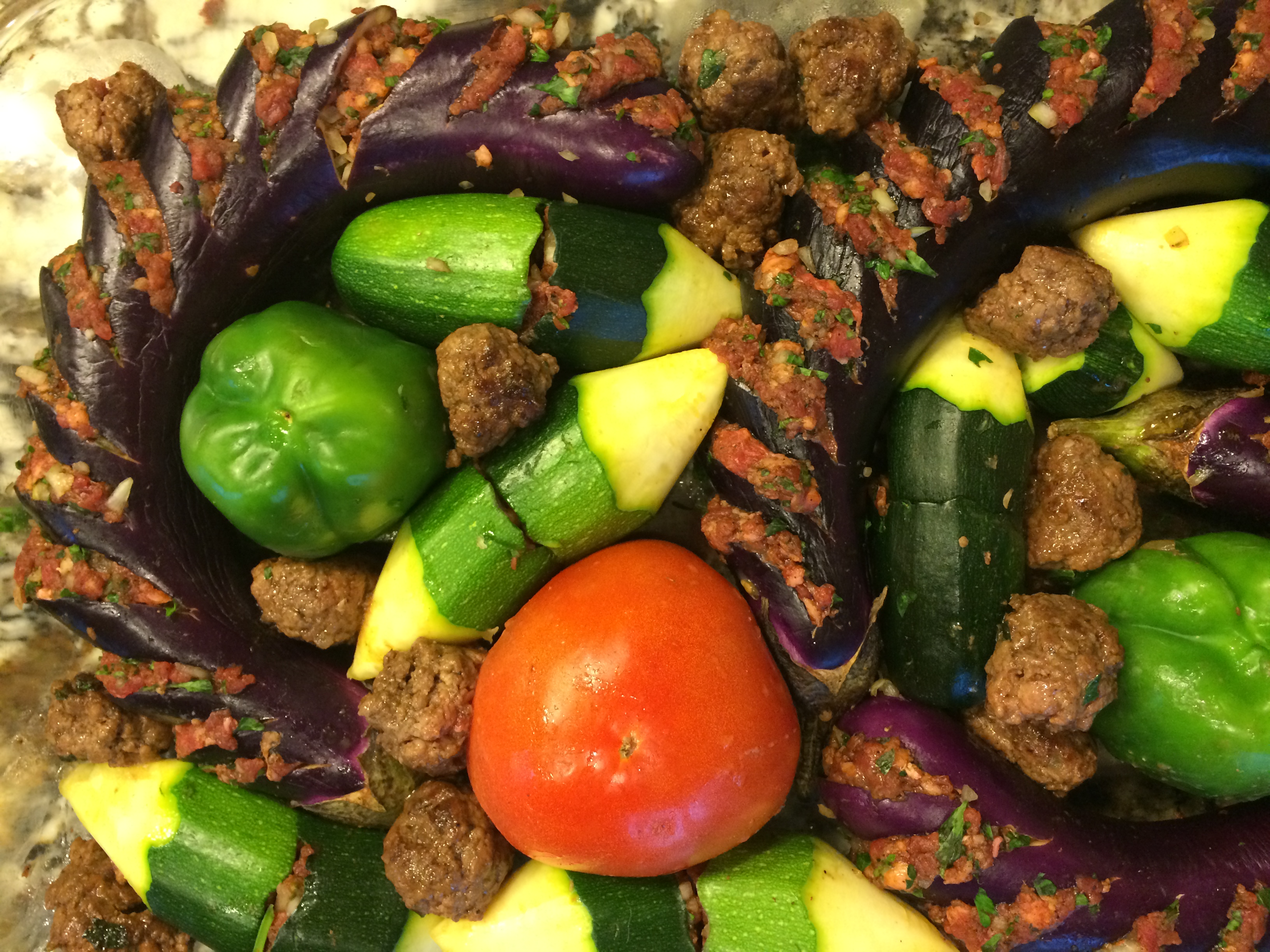 Clear baking tray with stuffed peppers, tomatoes, zucchini