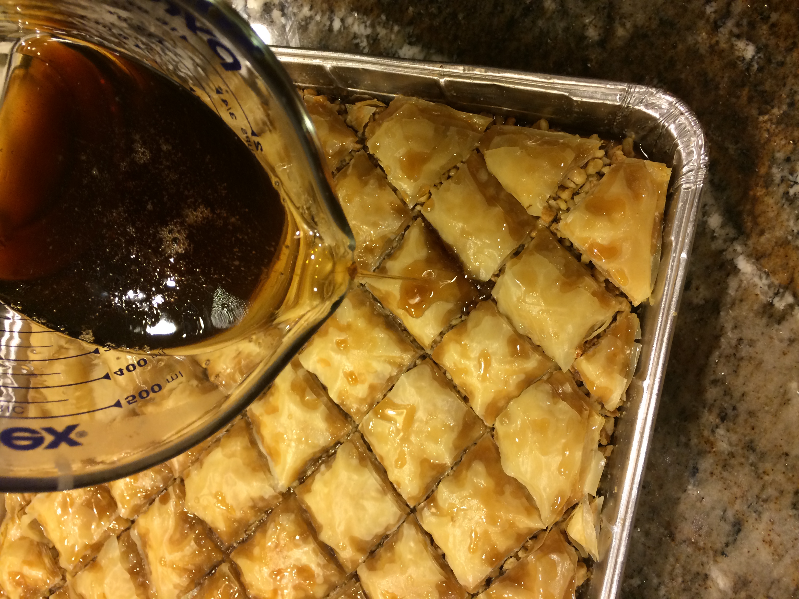 pouring simple syrup over the baked pistachio baklava