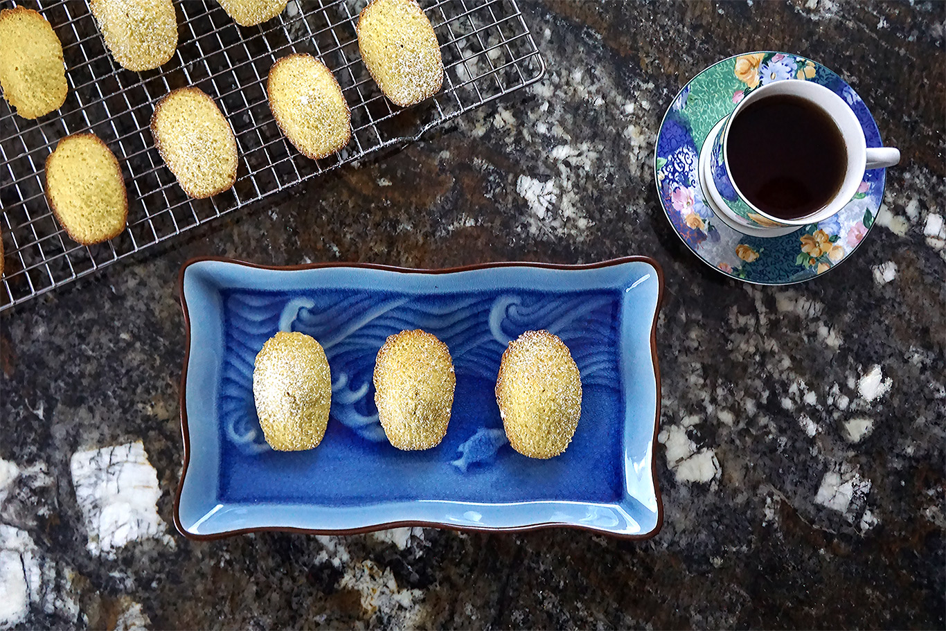 madeleines on a blue plate with a teacup nearby