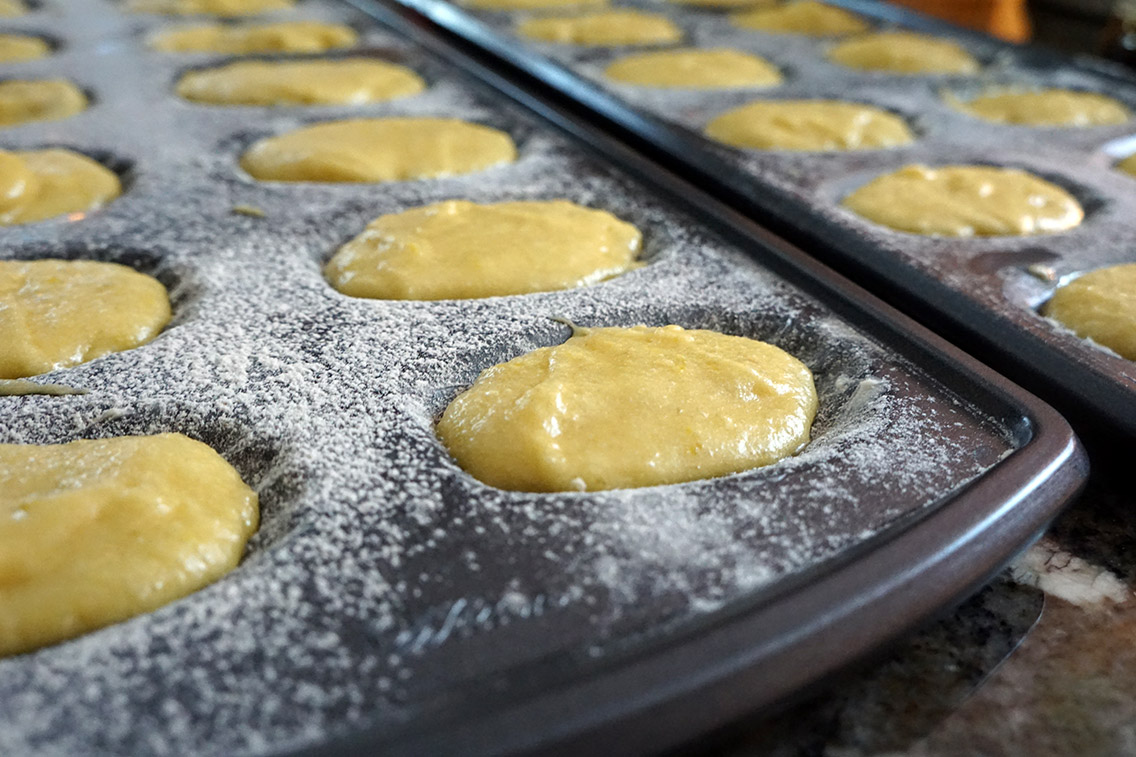 Buttered and floured madeleine pans filled with batter