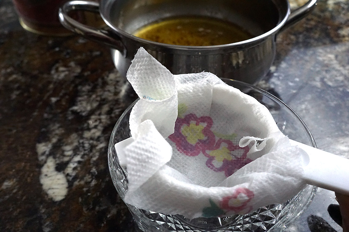Lining strainer with butter to strain clarified butter