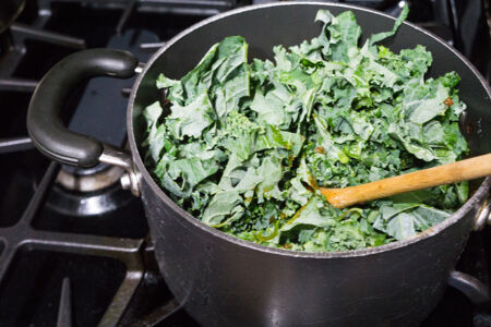 Adding kale to the tomato stew Adding kale to the tomato stew